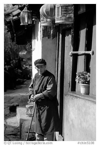 Naxi woman at the door of her wooden house. Lijiang, Yunnan, China