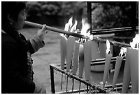 Woman Pilgrim lighting a large incense stick, Wannian Si. Emei Shan, Sichuan, China (black and white)