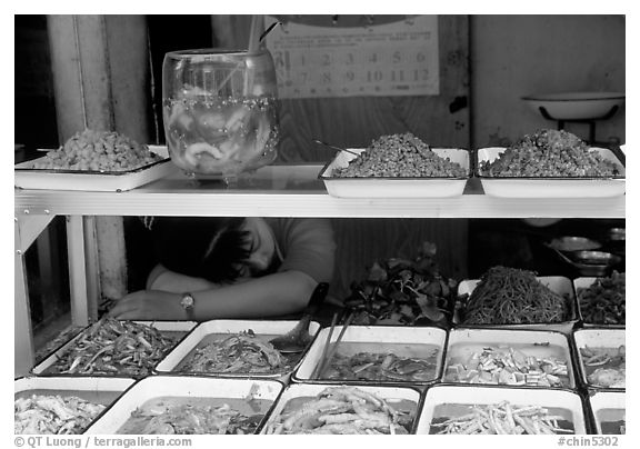 Vendor taking a nap at a food stall.. Chengdu, Sichuan, China (black and white)