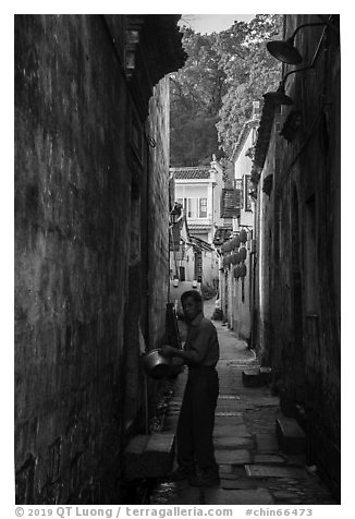Man using stream water in alley. Hongcun Village, Anhui, China (black and white)