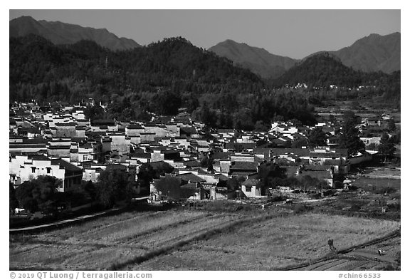 Field workers and village from above. Xidi Village, Anhui, China (black and white)