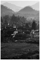 Villagers in fields and village in morning fog from above. Xidi Village, Anhui, China ( black and white)
