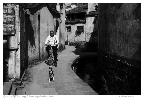 Dog and man on bike. Xidi Village, Anhui, China (black and white)