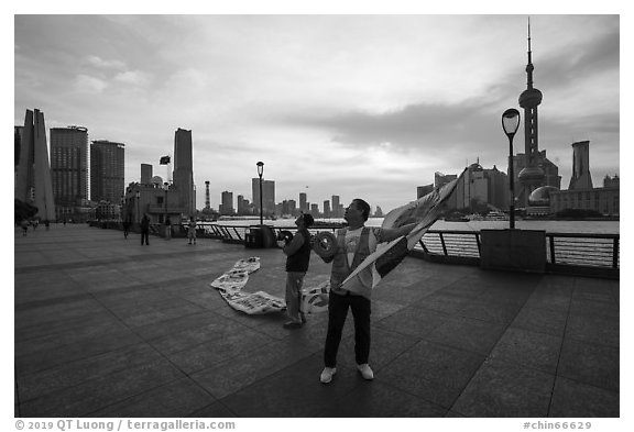 Men preparing to fly kites. Shanghai, China (black and white)
