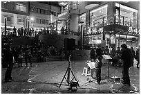 Tourists watch girl singing at night near the pier, Shueishe Village. Sun Moon Lake, Taiwan (black and white)