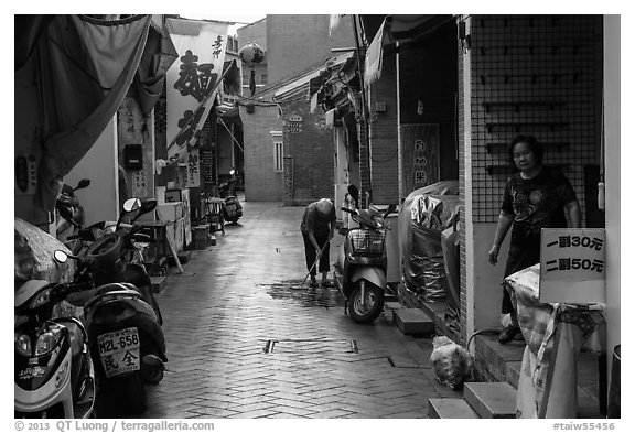 Woman cleaning in alley. Lukang, Taiwan (black and white)