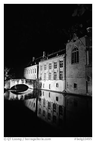 Houses and bridge reflected in canal at night. Bruges, Belgium