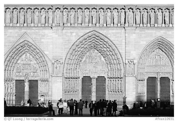 People standing in front of gates of Notre Dame Cathedral, late afternoon. Paris, France (black and white)
