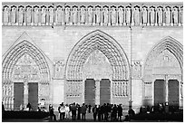 People standing in front of gates of Notre Dame Cathedral, late afternoon. Paris, France ( black and white)