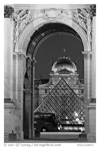 Louvre, pyramid, and bus seen through the Carousel Arch at night. Paris, France