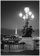 Bronze lamp post with scultpure on Pont Alexandre III, and Eiffel Tower at night. Paris, France ( black and white)