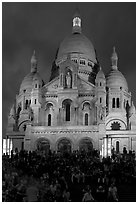 Tourists sitting on the stairs of the Sacre coeur basilic in Montmartre at night. Paris, France (black and white)