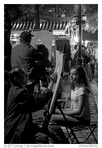 Artists drawing portraits at night on the Place du Tertre, Montmartre. Paris, France