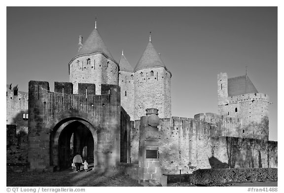 Main entrance of medieval city  with child and adult walking in. Carcassonne, France (black and white)