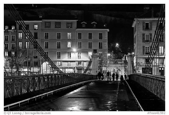 Pedestrians on suspension bridge at night. Grenoble, France (black and white)