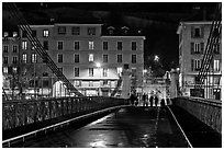 Pedestrians on suspension bridge at night. Grenoble, France (black and white)