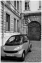 Tiny car on coblestone pavement in front of historic house. Lyon, France ( black and white)
