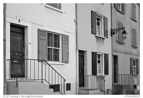 Facade of townhouses with colorful shutters. Arles, Provence, France (black and white)