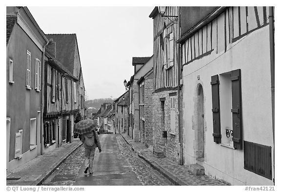 Pedestrian with umbrella in narrow street, Provins. France