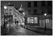Cobblestone street, lamps, and Sacre-Coeur basilica by night, Montmartre. Paris, France ( black and white)