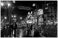 Metro entrance, boulevard, and Moulin Rouge on rainy night. Paris, France ( black and white)