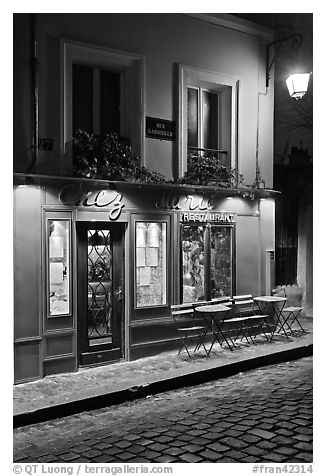 Restaurant with red facade and cobblestone street by night, Montmartre. Paris, France (black and white)