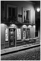 Restaurant with red facade and cobblestone street by night, Montmartre. Paris, France ( black and white)