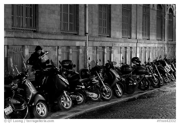 Scooters parked on a sidewalk at night. Paris, France (black and white)