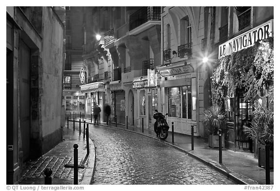 Street with cobblestone pavement and restaurants by night. Quartier Latin, Paris, France