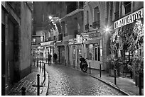 Street with cobblestone pavement and restaurants by night. Quartier Latin, Paris, France ( black and white)