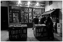 People reading in front of bookstore at night. Quartier Latin, Paris, France (black and white)