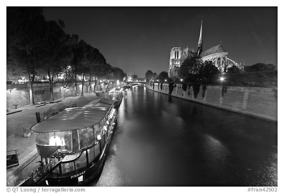 Quay, lighted boats, Seine River and Notre Dame at night. Paris, France (black and white)