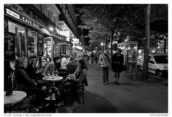 Cafe bar on sidewalk of a Grand Boulevard at night. Paris, France (black and white)
