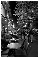 Couple walking by outdoor tables of cafe at night. Paris, France ( black and white)