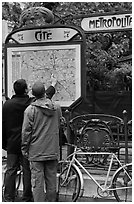 Men looking at a map of the Metro outside Cite station. Paris, France (black and white)