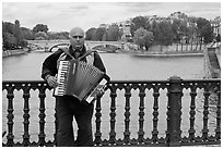 Street musician playing accordeon on River Seine bridge. Paris, France ( black and white)