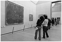 Tourists looking at a large impressionist painting of a lilly pond. Paris, France ( black and white)