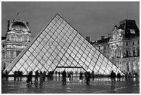 People standing in front of Louvre Pyramid by night. Paris, France (black and white)