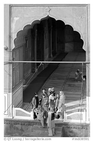 Women standing beneath arched entrance of prayer hall, Jama Masjid. New Delhi, India (black and white)