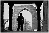 Man at entrance of ruined Quwwat-ul-Islam mosque. New Delhi, India ( black and white)