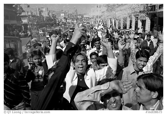 Young men celebrating and spraying wedding party in the street. Jodhpur, Rajasthan, India (black and white)