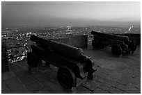 Cannons on top of Mehrangarh Fort, and city lights and dusk. Jodhpur, Rajasthan, India ( black and white)