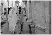 Women walking in narrow alley with blue walls. Jodhpur, Rajasthan, India ( black and white)