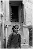 Schoolgirl standing in front of a house with blue tint. Jodhpur, Rajasthan, India ( black and white)