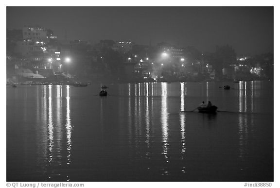 Rowboats and reflected lights on the Ganges River at dusk. Varanasi, Uttar Pradesh, India (black and white)
