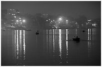 Rowboats and reflected lights on the Ganges River at dusk. Varanasi, Uttar Pradesh, India (black and white)