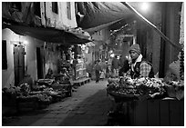 Flower vendor in  narrow old city alley at night. Varanasi, Uttar Pradesh, India (black and white)