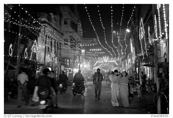 Women walking in street with illuminations. Varanasi, Uttar Pradesh, India