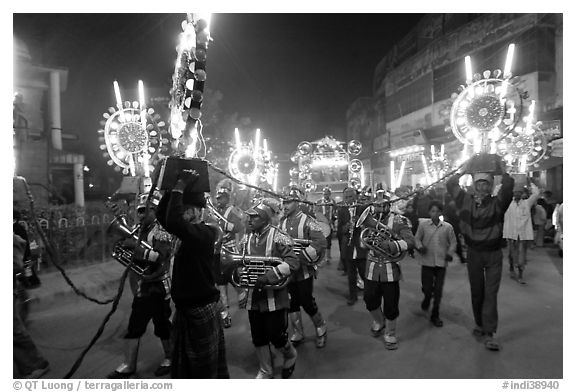 Musicians, men carrying lights, and carriage during wedding procession. Varanasi, Uttar Pradesh, India
