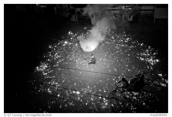 Man firing fireworks in middle of street ahead of wedding procession. Varanasi, Uttar Pradesh, India (black and white)